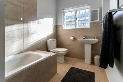 a bathroom with a tub and a toilet and a sink at Happy Hideaway in Hermanus