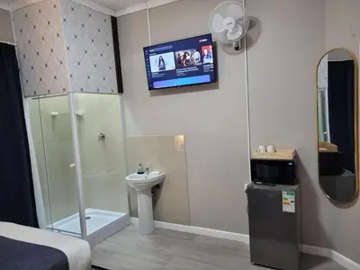 a bathroom with a shower toilet and a tv on the wall at Prime Executive Accommodation in Cape Town