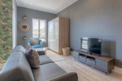 a living room with a couch and a flat screen tv at Trebuchet Studio Apartment in Somerset West
