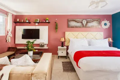 a bedroom with red walls and a bed and a couch at Caline VIP Luxury Jacuzzi &, Swimming Pool MEWS in Cape Town