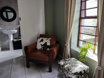 a brown chair in a bathroom with a window at Champers in Cape Town
