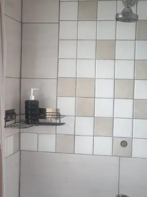 a bathroom with white tiled walls and a shelf at Spacious Double Room for Two with Pool, Braai, Gas Stove, Complete Kitchen, Fast WiFi and Private Bathroom in Cape Town