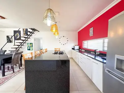 a kitchen with red walls and a dining room at Spacious Double Room for Two with Pool, Braai, Gas Stove, Complete Kitchen, Fast WiFi and Private Bathroom in Cape Town