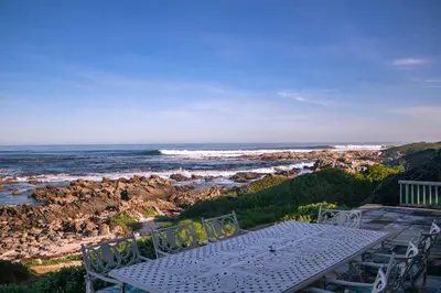 a white table and chairs sitting on top of a beach at Seascape, Vermont Retreat in Hermanus