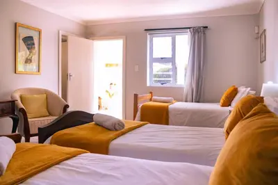 a hotel room with three beds and a window at Seascape, Vermont Retreat in Hermanus