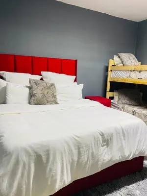 a bedroom with a large bed with a red headboard at Brooklyn Queens and Kings Guesthouse in Cape Town