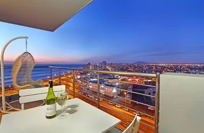 a table with two wine glasses and a view of a city at Private Blouberg Beachfront Getaway in Cape Town