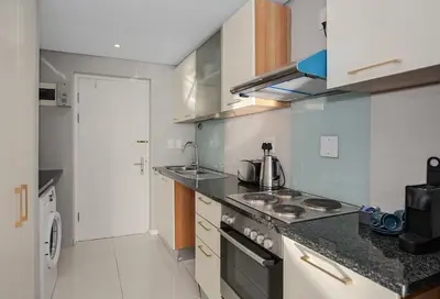 a small kitchen with a stove and a sink at Private Blouberg Beachfront Getaway in Cape Town