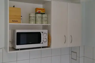 a microwave in a kitchen with white cabinets at Cape Explore in Cape Town
