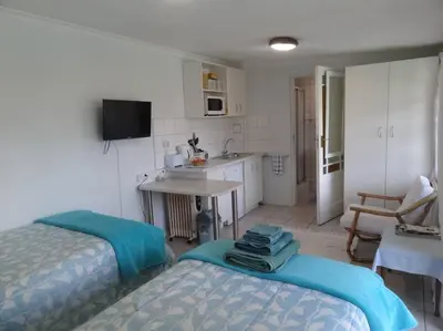 a room with two beds and a kitchen with a table at Cape Explore in Cape Town