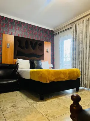 a bedroom with a large bed with a yellow blanket on it at Parow city -Star Legend Lodge in Cape Town