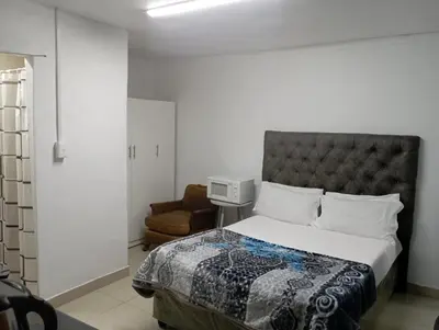 a bedroom with a bed and a chair at The trout Lodge in Cape Town