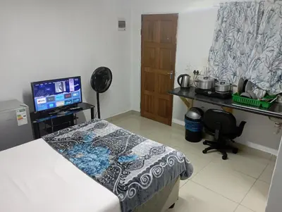 a room with a bed and a desk with a television at The trout Lodge in Cape Town