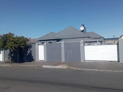 a house with a fence and a white garage at The trout Lodge in Cape Town