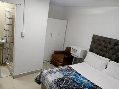 a hotel room with a bed and a chair at The trout Lodge in Cape Town