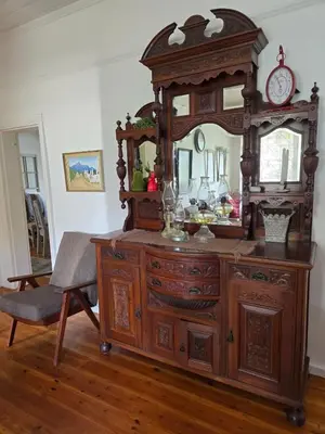 a large wooden dresser with a mirror and a chair at Greyt House selfcatering house in Greyton SA in Greyton