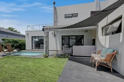 a white house with chairs and a swimming pool at Spacious Double Room with Pool, Free WiFi, Self-Catering Kitchen in Cape Town