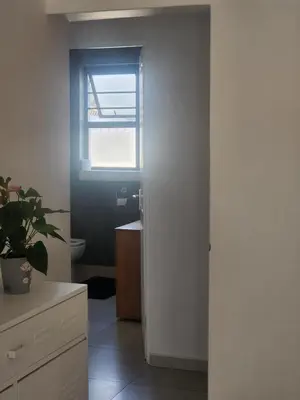 a bathroom with a toilet and a window and a sink at Spacious Double Room with Pool, Free WiFi, Self-Catering Kitchen in Cape Town