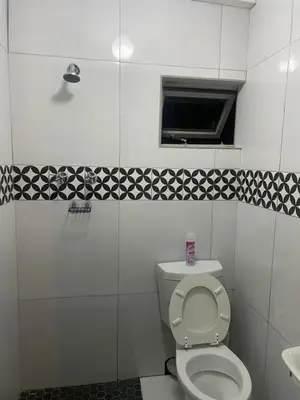 a white bathroom with a toilet and a window at Flaming Place in Cape Town