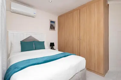 a bedroom with a white bed and a wooden cabinet at Serena Inn Room 3 in Cape Town