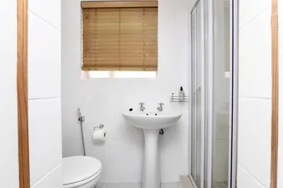 a white bathroom with a toilet and a sink at Serena Inn Room 3 in Cape Town