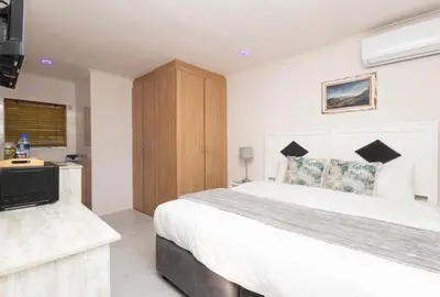 a bedroom with a large white bed and a television at Serena Inn room 2 in Cape Town