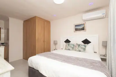 a bedroom with a large bed and a wooden cabinet at Serena Inn room 2 in Cape Town