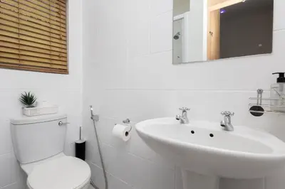 a white bathroom with a toilet and a sink at Serena Inn room 2 in Cape Town