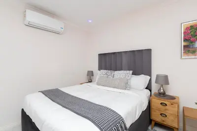 a bedroom with a white bed with a black headboard at Serena Inn room 4 in Cape Town