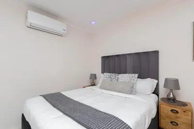 a bedroom with a white bed with a black headboard at Serena Inn room 4 in Cape Town