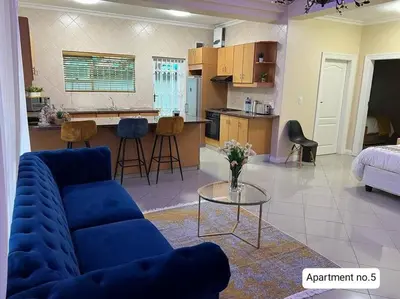 a living room with a blue couch and a kitchen at Serena Inn Apartment no5 Self Catering in Cape Town