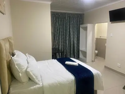 a bedroom with a bed with a blue and white blanket at Sabbath Lodge VIP in Cape Town