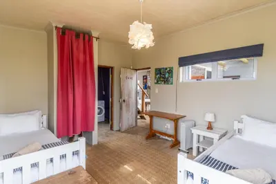 a bedroom with two beds and a red curtain at Mountain View in Bettyʼs Bay