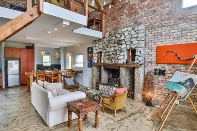 a living room with a brick wall with a fireplace at Mountain View in Bettyʼs Bay