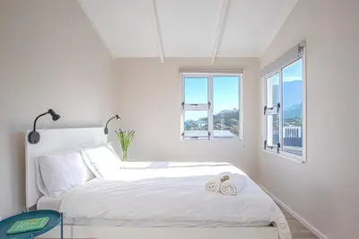 a white bedroom with a bed with two towels on it at Beautiful family beach cottage! in Pringle Bay
