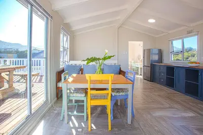 a kitchen with a wooden table and yellow chairs at Beautiful family beach cottage! in Pringle Bay