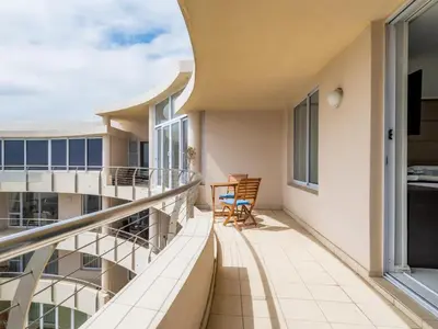 a balcony with a table and chairs on a building at Lagoon Shoreline Penthouse in Cape Town