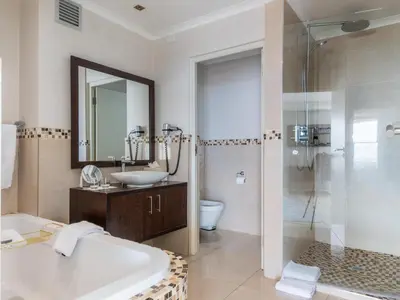 a bathroom with a tub and a sink and a shower at Lagoon Shoreline Penthouse in Cape Town
