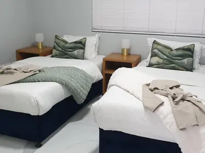 a bedroom with two beds and two night stands at Lagoon Shoreline Penthouse in Cape Town
