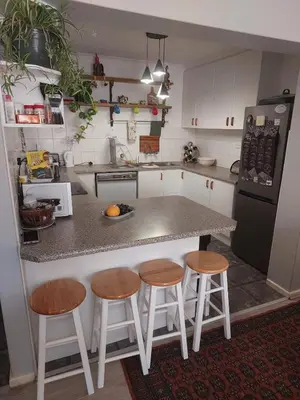 a kitchen with a counter with stools and a refrigerator at Self-Catering Apartment near beach in Strand
