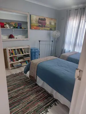 a bedroom with two beds and a rug at Self-Catering Apartment near beach in Strand