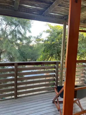 a rocking chair on a porch with a fence at Sunset Beach Studio Apartment in Cape Town