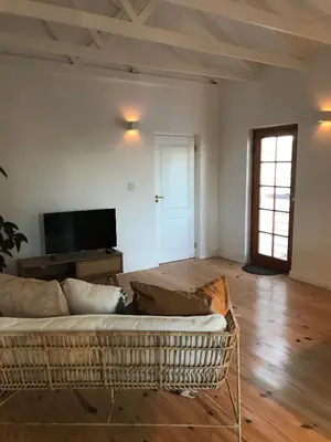a living room with a couch and a television at Sunset Beach Studio Apartment in Cape Town