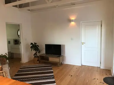 an empty living room with a flat screen tv at Sunset Beach Studio Apartment in Cape Town