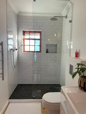 a bathroom with a shower with a toilet and a sink at Sunset Beach Studio Apartment in Cape Town