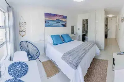 a white bedroom with a bed and a fan at Beach Front Sea View Apartment, Table View in Cape Town