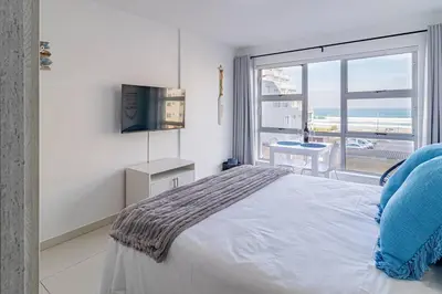 a bedroom with a bed and a large window at Beach Front Sea View Apartment, Table View in Cape Town
