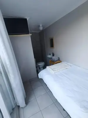 a bedroom with a white bed and a toilet at Cozy Business overnighter in Bellville