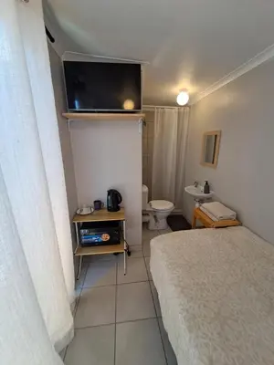 a small bedroom with a bed and a toilet at Cozy Business overnighter in Bellville