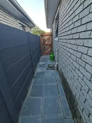 an alley with a brick wall and a green bucket at Cozy Business overnighter in Bellville